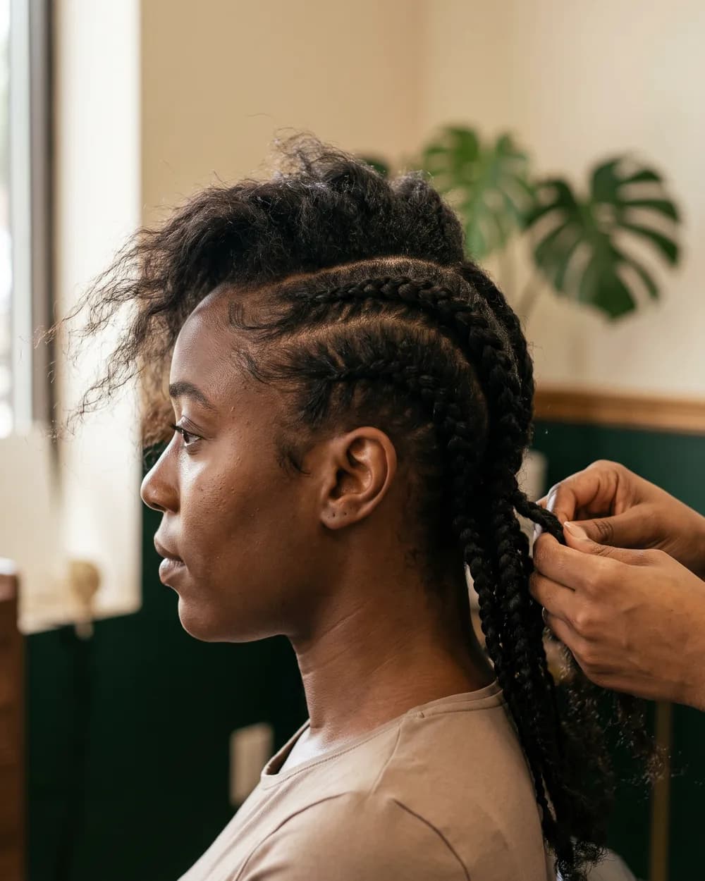 A TF Loft stylist braiding a client's hair in the studio
